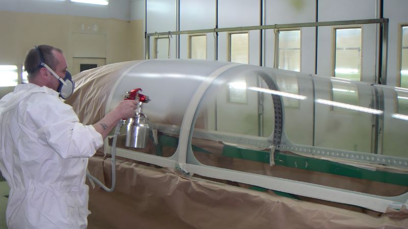 Technician spraying Protectapeel spray on peelable protective coating directly onto an aircraft canopy