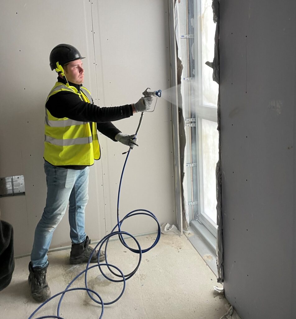 construction worker spraying Protectapeel to a window