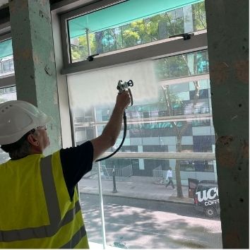 Spraying Protectapeel on a glass panel to protect from construction damage