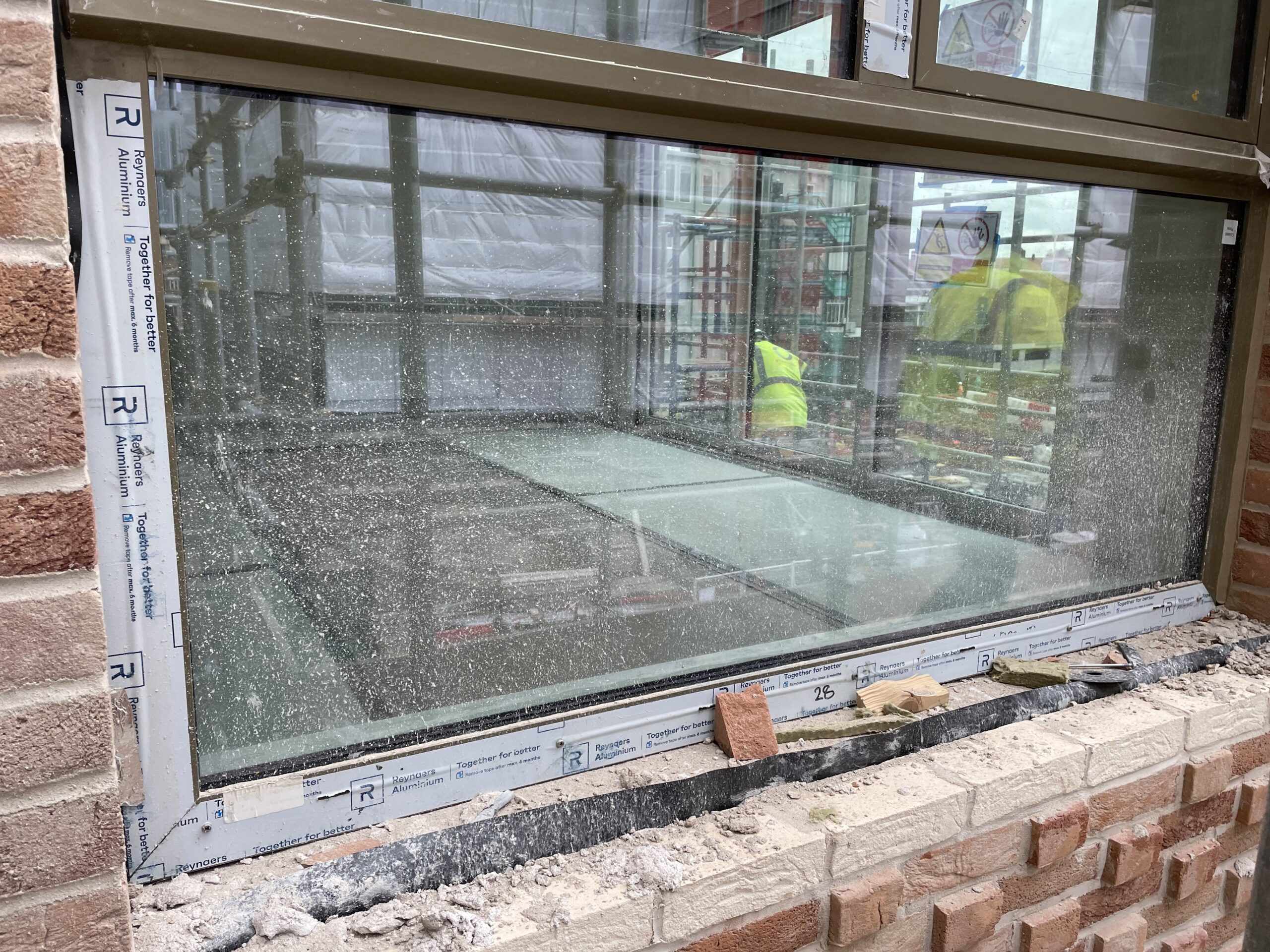 Construction site dirt, mortar and dust build up on an installed window on a construction project