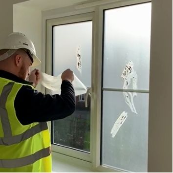 Peeling Protectapeel from a window showing mortar being removed with the coating, leaving clean windows