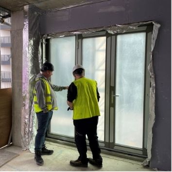 two construction workers looking at glass facade that was protected from surface damage using Protectapeel spray on protective coating